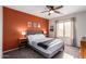 Bright bedroom with a gray bed, orange accent wall, and ceiling fan at 30052 N Desert Willow Blvd, San Tan Valley, AZ 85143