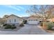 House exterior featuring a two-car garage and mature trees at 7873 W Fetlock Trl, Peoria, AZ 85383