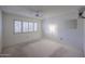 A light filled bedroom featuring neutral carpeting, ceiling fan, and window with light-filtering shutters at 13359 W Ballad Dr, Sun City West, AZ 85375