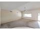 Spacious living room featuring a vaulted ceiling, large windows, and neutral carpeting at 13359 W Ballad Dr, Sun City West, AZ 85375