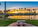 Tranquil lake view at sunset, palm trees silhouette against the sky at 16807 W Berkeley Rd, Goodyear, AZ 85395