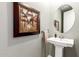 Elegant powder room with pedestal sink and large framed art at 20385 W Vista Paseo Dr, Buckeye, AZ 85396