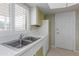 Kitchen area with double sink, green cabinets, and white appliances at 10845 W Kaibab Dr, Sun City, AZ 85373