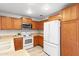 Kitchen with oak cabinets, white appliances, and light floors at 11612 W Lee Ln, Youngtown, AZ 85363