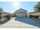 Single-story house with tan exterior, two-car garage, and landscaped front yard at 15797 W Remington Dr, Surprise, AZ 85374