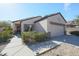 Single-story house with tan exterior, two-car garage, and landscaped front yard at 15797 W Remington Dr, Surprise, AZ 85374