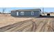 Rear view of a gray manufactured home with a large undeveloped lot at 53275 W Adele Rd, Maricopa, AZ 85139