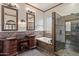 Elegant bathroom featuring a tiled walk-in shower and a soaking tub, complemented by decorative sconces at 1231 W Hawken Way, Chandler, AZ 85286