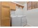 Bright laundry room with white washer and dryer, light wood cabinets and a window with blinds at 1231 W Hawken Way, Chandler, AZ 85286
