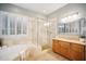 Bright bathroom featuring a soaking tub, glass shower enclosure, and natural stone finishes at 27600 N 130Th Ave, Peoria, AZ 85383