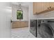 Bright laundry room featuring modern washer/dryer, stylish tile floor, and ample cabinet space at 6040 E Lafayette Blvd, Scottsdale, AZ 85251