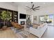 Open living room with hardwood floors, a cozy fireplace, modern fan and a sliding door to the exterior at 19702 E Melissa Pl, Queen Creek, AZ 85142