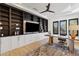 Home office with custom built-in shelving, TV, ceiling fan, and a stylish wooden desk with contemporary furnishings at 19702 E Melissa Pl, Queen Creek, AZ 85142