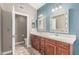 Bathroom with double sinks, wood cabinets, decorative mirrors, and an open doorway to the toilet at 905 E Knight Ln, Tempe, AZ 85284