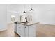 An open-concept kitchen island with a sink, white cabinets, and stainless steel appliances, and light wood flooring at 7637 W Minton St, Laveen, AZ 85339