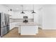 Modern white kitchen featuring an island with a sink, stainless steel appliances, and light wood flooring at 7637 W Minton St, Laveen, AZ 85339