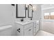 Bright bathroom featuring double sinks, white cabinets, black hardware, and neutral tile flooring at 7641 W Minton St, Laveen, AZ 85339