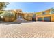 Stunning yellow home showcasing a paver driveway and grand entryway with pillars and black iron accents at 16149 E Thistle Dr, Fountain Hills, AZ 85268