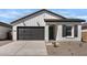 Charming single-story home featuring a gray garage door and complementary desert landscaping at 16590 N Dante Way, Maricopa, AZ 85138