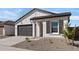 Charming single-story home featuring a gray garage door and complementary desert landscaping at 16590 N Dante Way, Maricopa, AZ 85138