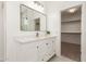 Bathroom featuring a white vanity, framed mirror, decorative plant and an open doorway to the walk-in closet at 135 E Julian Dr, Gilbert, AZ 85295