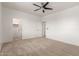 Spacious carpeted bedroom featuring a ceiling fan, neutral walls, and doorways to a walk-in closet and hallway at 135 E Julian Dr, Gilbert, AZ 85295
