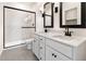 Bathroom showcasing double sinks, dark hardware, white cabinetry, tiled floors and glass shower, for spa-like feel at 16580 N Dante Way, Maricopa, AZ 85138