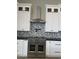 Modern kitchen with stainless steel oven, white cabinets, mosaic tile backsplash, and a sleek range hood at 3703 S Avenida De Angeles --, Gold Canyon, AZ 85118