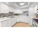 Bright kitchen with white cabinets, mosaic backsplash, and modern lighting fixture at 6819 E Grandview Dr, Scottsdale, AZ 85254