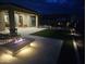 A backyard with a modern stone fire pit, patio seating, and a pergola-covered dining area, creating an inviting outdoor living space at 11578 W Montansoro Ln, Peoria, AZ 85383
