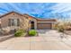 One-story house with tan exterior, landscaped yard, and two-car garage at 1727 N 213Th Dr, Buckeye, AZ 85396