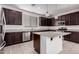 Kitchen boasts dark wood cabinets, granite island, and stainless steel appliances at 1727 N 213Th Dr, Buckeye, AZ 85396