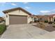 Front view of a beige house with a two-car garage and drought-tolerant landscaping at 26180 W Firehawk Dr, Buckeye, AZ 85396