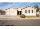 Tan house with a three-car garage, landscaping, and a large front yard at 3410 N 131St Ln, Litchfield Park, AZ 85340