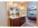 Bathroom with a double vanity, a large mirror, and a view into the bedroom at 16140 W Almeria Rd, Goodyear, AZ 85395