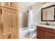 Well-lit bathroom featuring a tub-shower, vanity with granite counters, and wood cabinetry for ample storage at 2233 N Middlecoff Dr, Mesa, AZ 85215
