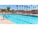 Sparkling community pool surrounded by lounge chairs, umbrellas, and swaying palm trees, perfect for relaxation at 2233 N Middlecoff Dr, Mesa, AZ 85215