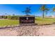 Apache Wells Country Club entrance sign with sculpture, set amongst palm trees and manicured landscaping at 2233 N Middlecoff Dr, Mesa, AZ 85215