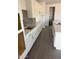 Elegant kitchen with white cabinets, gray backsplash, an island with stainless steel sink, and spacious pantry at 31277 N 130Th Ave, Peoria, AZ 85383