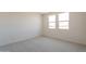 A bright, empty bedroom is seen, showcasing neutral carpet and multiple large windows at 11029 E Ulysses Ave, Mesa, AZ 85212