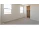 Bright bedroom with carpet, two large windows, and an open closet space at 11029 E Ulysses Ave, Mesa, AZ 85212