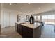 Bright kitchen island with stainless steel sink, dark brown cabinets, and seating with a view to the living room at 11029 E Ulysses Ave, Mesa, AZ 85212