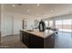 Bright kitchen island with stainless steel sink, dark brown cabinets, and seating with a view to the living room at 11029 E Ulysses Ave, Mesa, AZ 85212