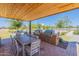 Outdoor kitchen area under wooden roof featuring built-in grill, dining table, chairs, and landscaped surroundings at 11029 E Ulysses Ave, Mesa, AZ 85212