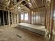 Bedroom in progress featuring wooden framing, windows, and stacks of drywall ready for installation at 22820 E Lords Way, Queen Creek, AZ 85142