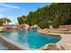 Backyard pool with rock features, a water slide, and a built-in spa, set against a backdrop of lush greenery at 321 N Portland Ave, Gilbert, AZ 85234