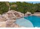 Backyard pool featuring a natural rock waterfall and slide, surrounded by lush greenery at 321 N Portland Ave, Gilbert, AZ 85234