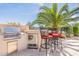 Built-in outdoor kitchen with grill, mini-fridge, and seating for two at 1806 E Azafran Trl, Queen Creek, AZ 85140