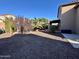 Landscaped backyard with gravel, mature trees, and a patio area at 15936 W Canterbury Dr, Surprise, AZ 85379