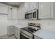 A modern kitchen featuring stainless steel appliances, sleek white countertops, and stylish gray cabinets at 18526 E Swan Dr, Queen Creek, AZ 85142